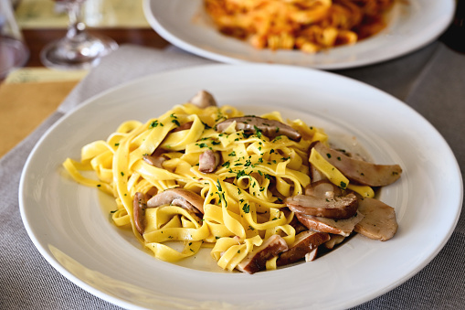 close up of tasty tagliatelle with porcini mushrooms on a plate in a restaurant.