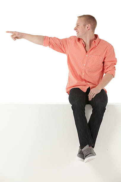 istock Man sitting on the ledge of a wall and pointing 174862120