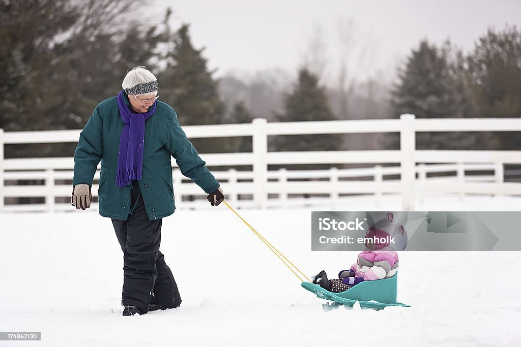 Grandma Pulling Granddaughter in Sled Little girl being pulled in the sled by Grandma. Snow Stock Photo