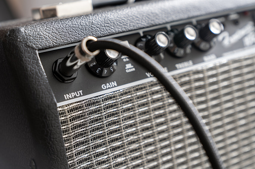 Close up of electric guitar amplifier with a audio cable plugged into jack. Shallow depth of field
