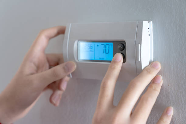 istock Hand press indoor room thermostat to lower the temp 1748626409