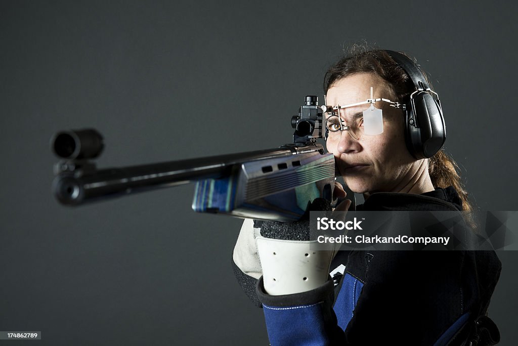 Woman sport shooter with a .22 rifle "Moody toned black and white portrait of a sport shooter using a 22 caliber rifle with special sights, glasses and ear protectors." 40-49 Years Stock Photo