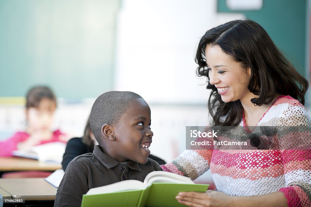 Profesor ayudando a los estudiantes para leer primaria - Foto de stock de Africano-americano libre de derechos