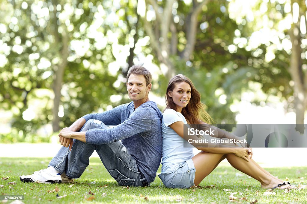 Assis dos à dos dans le parc - Photo de Adulte libre de droits