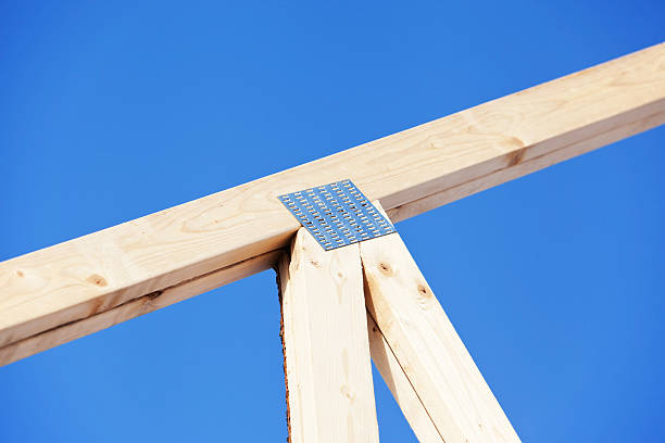 A portion of a house roof truss against a clear blue sky.