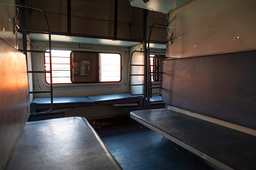 This image provides an inside look at an Indian sleeper train in Goa, capturing the essence of long-distance travel in the country. The sleeper compartments are designed for basic comfort, featuring bunk beds aligned along both sides of the coach. Personal belongings, luggage, and the occasional snack vendors fill the narrow corridors, adding to the train's unique atmosphere. The photograph aims to showcase the intimate nature of this communal travel experience, highlighting how people from diverse backgrounds share a confined space for the journey's duration. It offers viewers a window into what can be both a nostalgic and eye-opening aspect of travel within India.