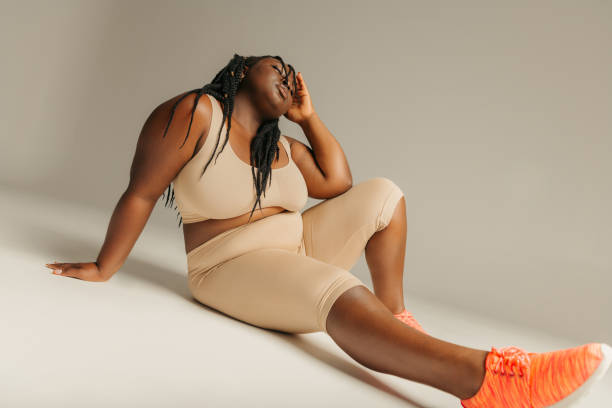istock Young plus size African woman in sportswear looking relaxed while sitting against studio background 1748641942