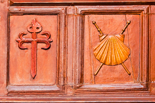 Santiago de Compostela traditional cross and scallop symbol carved in  a church door, wood material . Camino de Santiago, Santiago de Compostela, Galicia, Spain.