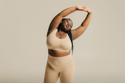 Attractive African plus size woman in underwear radiating self-love while standing on studio background