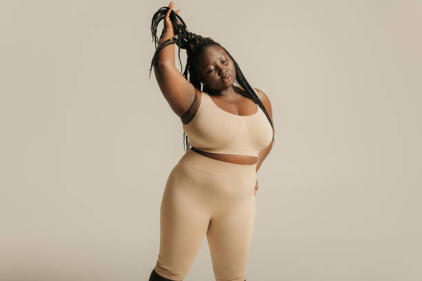 istock Beautiful African plus size woman in underwear radiating self-love while adjusting her dreadlocs on studio background 1748649946