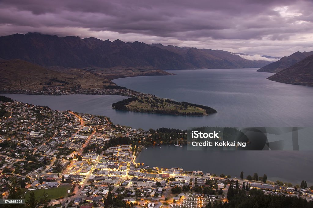 Queenstown at dusk Queenstown lights up at night, with the Remarkables looming behind it. Graduated ND filter used here and to lend purple hue. Aerial View Stock Photo