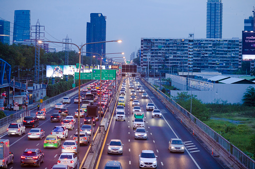 High angle view of  Chalem Maha Nakhon Expressway toll road in Bangkok during traffic jam and sunset scene with skyline of Bangkok Phloen Chit. View to north