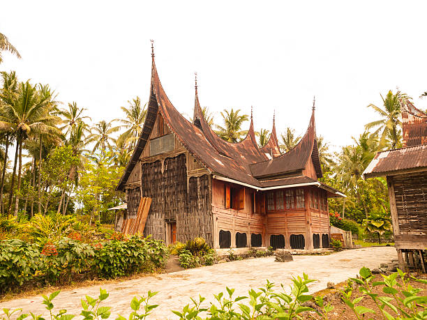 Traditional Toba Batak House in Sumatra, Indonesia  "Traditional Batak house at the lake Toba in Sumatra, Indonesia. Made of wood, similar to nautical vessel. Around are palm trees and some flowers." danau toba lake stock pictures, royalty-free photos & images