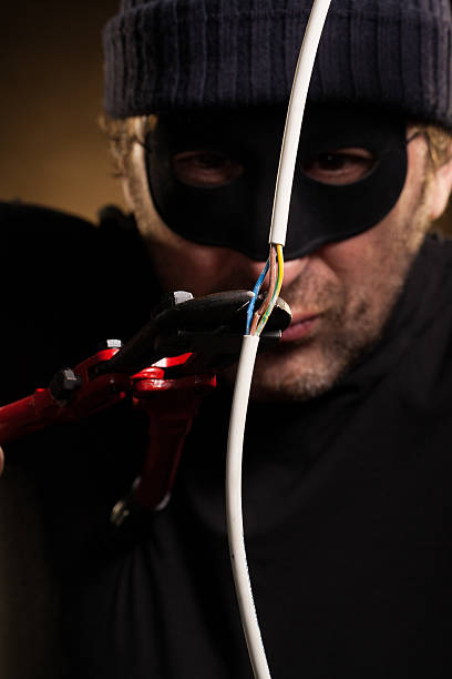 Thief Cutting Electric Wire with Nippers stock photo