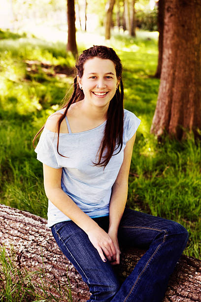 istock Pretty hippie in jeans and dreadlocks sits on log smiling 174867577