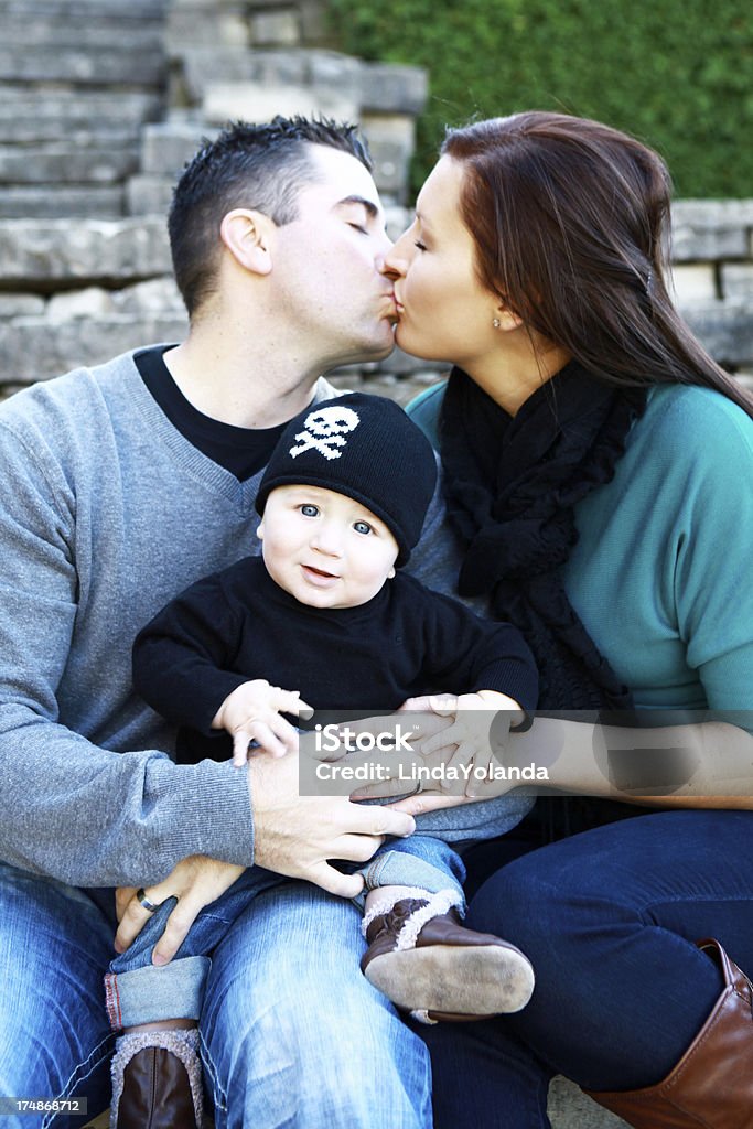 Giovane coppia Baciare il loro bambino in loro possesso - Foto stock royalty-free di 0-11 Mesi