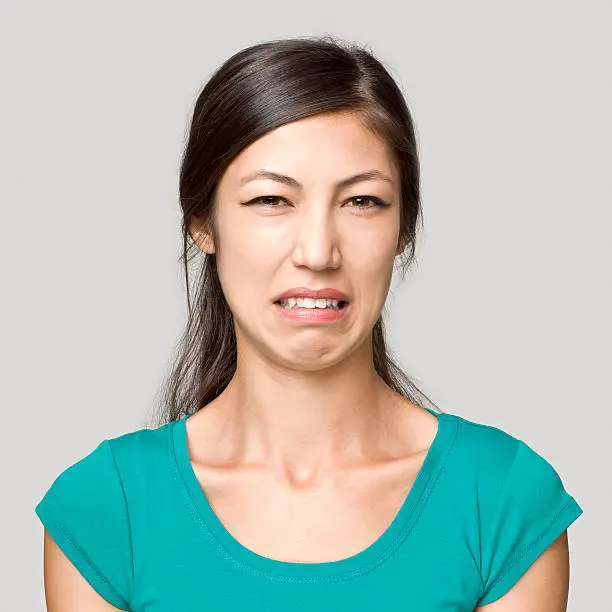 "Close up portrait of a young woman making a disgusting face expression, studio shot"