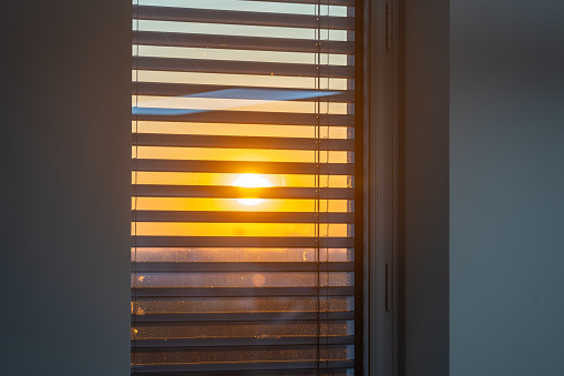 Sun seen through a window with external venetian blinds