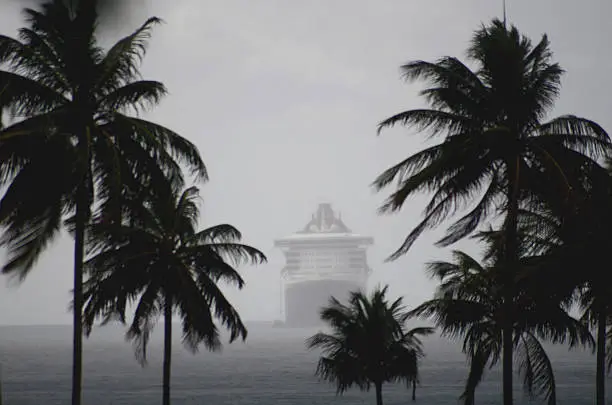 Photo of cruise ship in misty rainy seas among palm trees