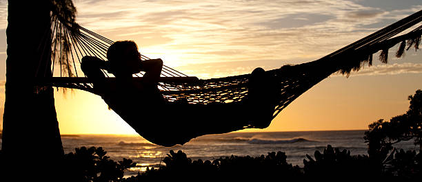 A woman relaxing in  a hamock by a beautiful tropical beach. Silhouette.