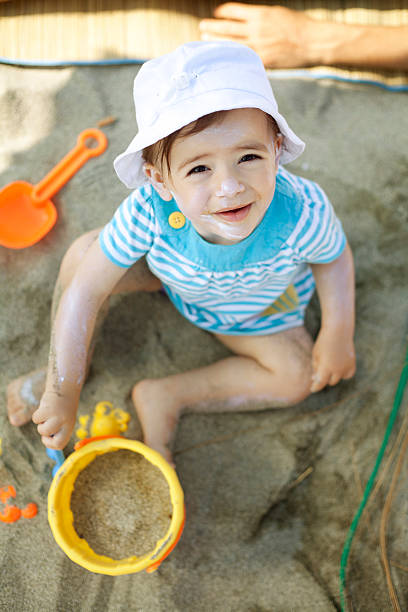 istock baby girl playing in the sand 174869438
