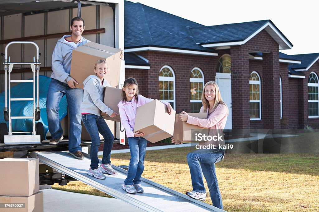 Family moving house, unloading truck Moving house.  Family loading or unloading moving van. Moving Van Stock Photo