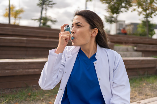 Healthcare Worker Using Asthma Inhaler Outside Hospital
