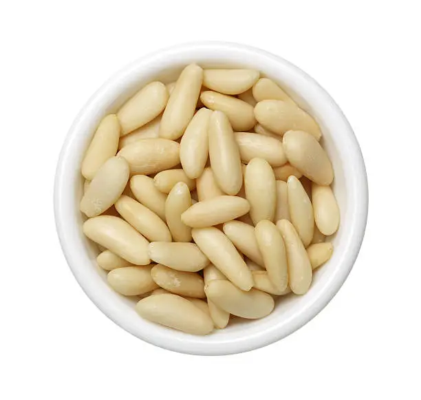 Top view of white bowl full of Pine nuts
