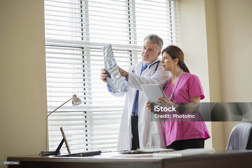 Los médicos con tableta Digital examen de rayos X del informe por la ventana - Foto de stock de 40-44 años libre de derechos