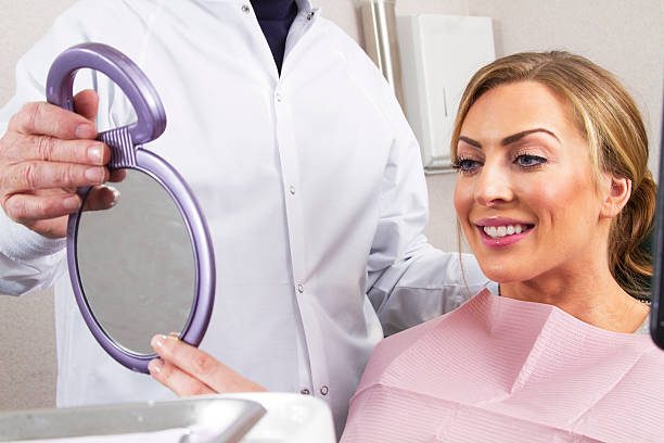 Dental patient smiles in mirror stock photo