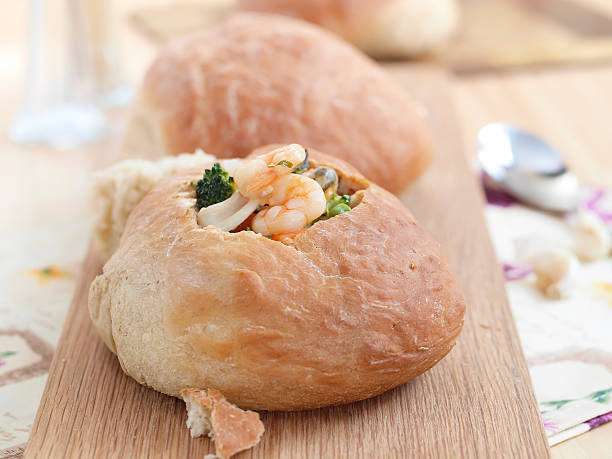istock wood serving board with two bread bowls of seafood chowder 174873585