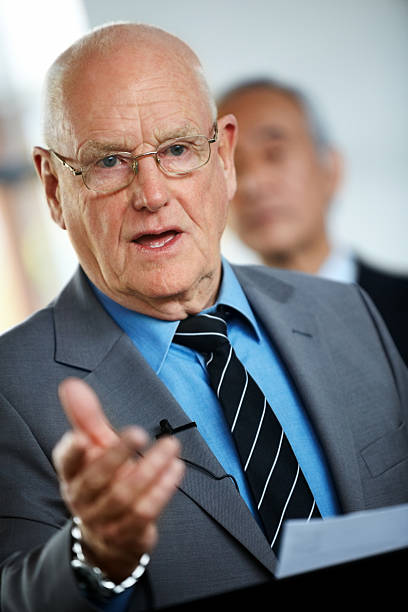Senior Caucasian businessman giving a speech to people during a seminar