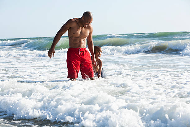 istock Father and son playing in surf 174874328