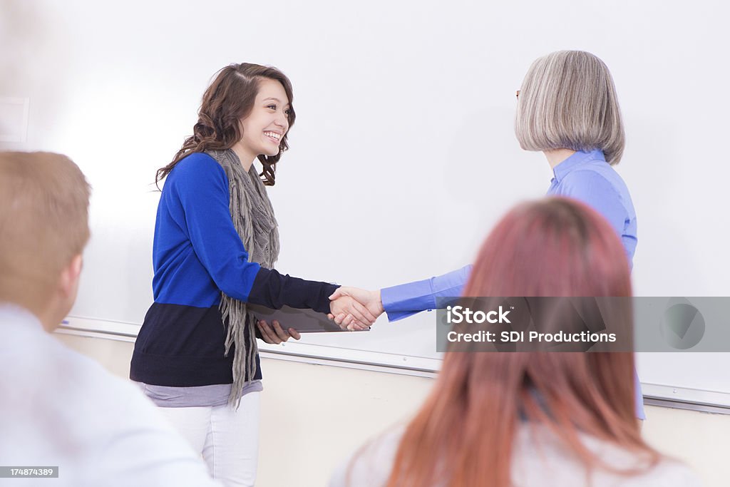 Pretty college student agitación el profesor en clase de la mano - Foto de stock de Adulto libre de derechos