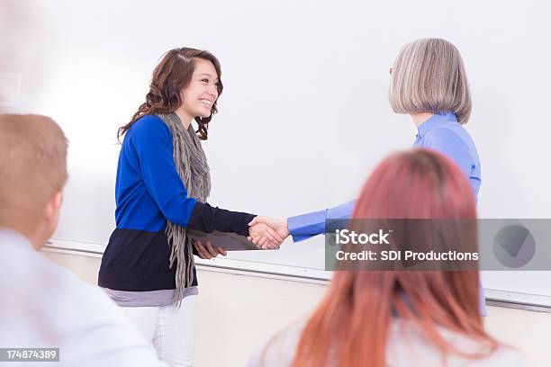 Pretty College Student Agitación El Profesor En Clase De La Mano Foto de stock y más banco de imágenes de Adulto