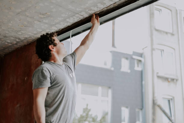 istock A young caucasian man repairing a window opening while and cleaning the frames with his hand 1748746879