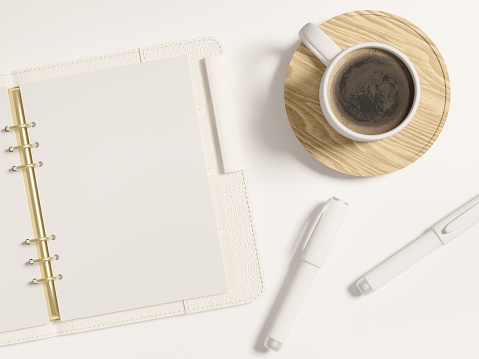 Ring bound A5 leather notebook mockup showing open blank planner spread with copy and design presentation space. White stationery and coffee cup. Top view of a flatlay on a desk. Realistic 3D render.