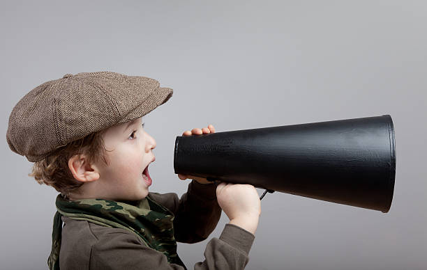 istock Little boy with newsboy cap shouting on old fashioned megaphone 174875254