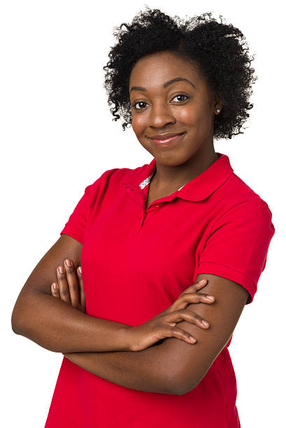 Young, confident black woman in red shirt with arms crossed Portrait of a young woman on a white background. polo shirt stock pictures, royalty-free photos & images