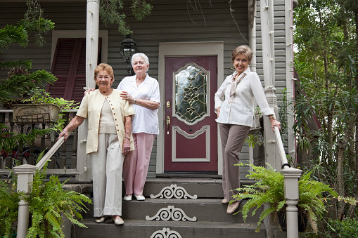 Group of elderly women (80s) standing at front door of home.