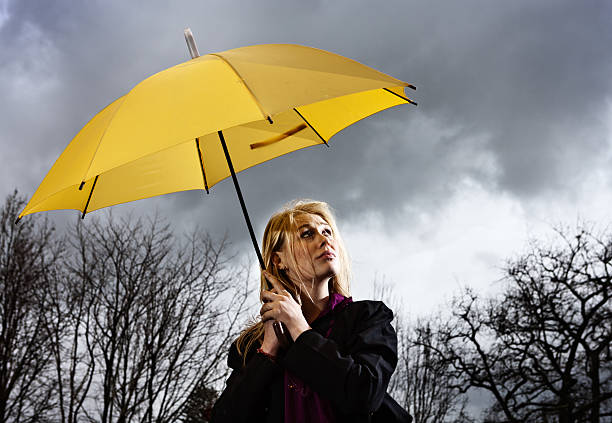 ここで、は、シルバーの裏地。美しいブロンドの雷雨 - umbrella women storm yellow ストックフォトと画像