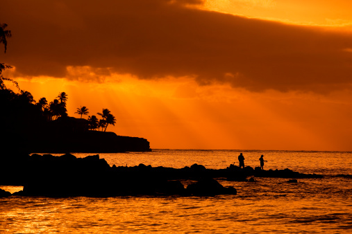 Subject: Sport fishing in romantic sunset over Poipu beach in southern the side of the tropical paradise island of Kauai.