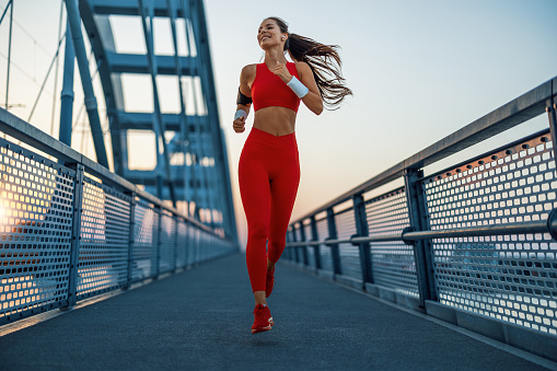 Athletic woman running during sunset in the city.Young woman jogger is running outdoors.