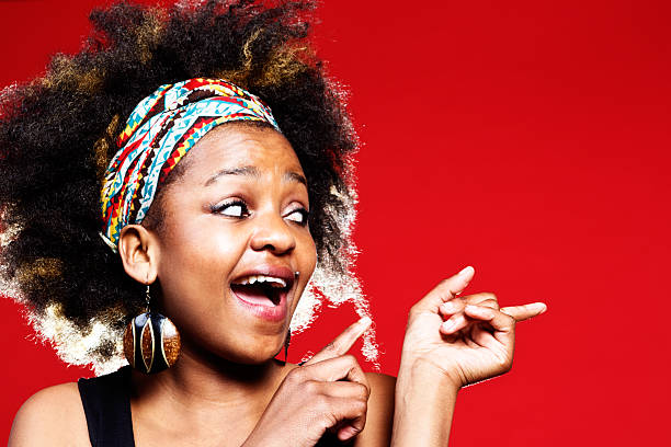 istock Cute afro-haired wman points to space at side, laughing 174876840