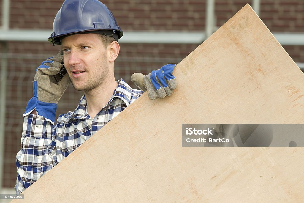 Auftragnehmer von Bauarbeiten hält ein Stück Holz - Lizenzfrei Am Telefon Stock-Foto
