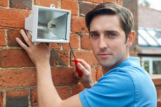istock Man Fitting Security Light To Wall Of House 174877313