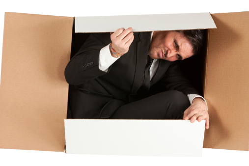 Businessman packed in a cardboard box