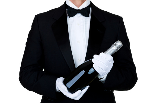 Man wearing a tuxedo and holding a bottle of champagne