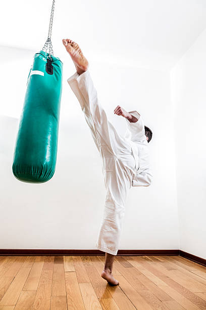 jeune homme pratiquant le arts martiaux - karate punching bag caucasian leisure activity photos et images de collection