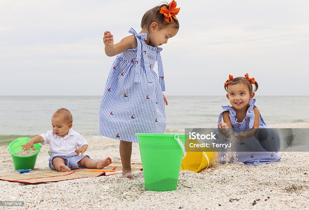 Day at the Beach "Twin sisters and their brother play in the sand at the beach in Naples, Florida." 12-23 Months Stock Photo